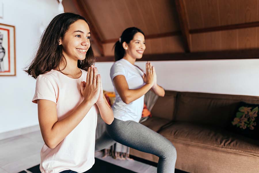 Employee Benefits - Young Woman and Child Doing Yoga and Stretching Together in Their Home