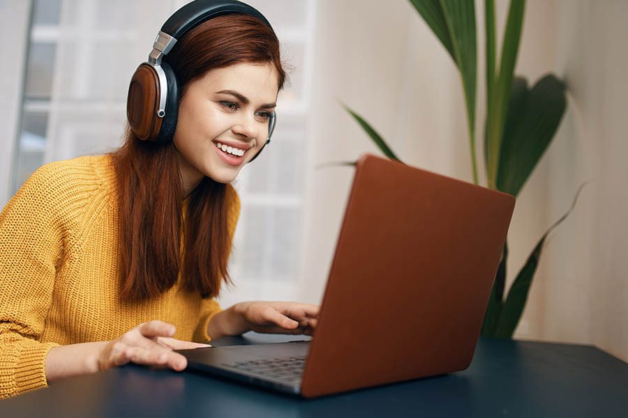 Video Library - Woman Smiling and Working on a Laptop at Her Dining Room Table at Home