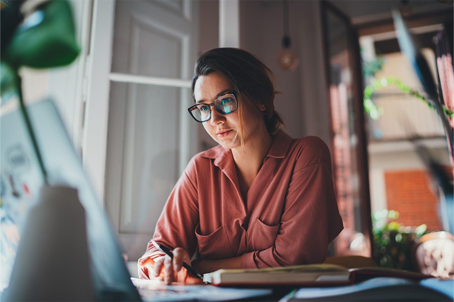 Home Policy Review - Woman Sitting at Desk at Home By the Window Looking at Laptop